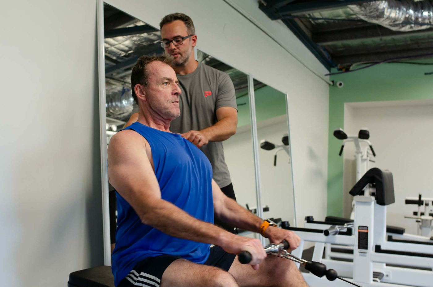 Mathew cueing a client's shoulder position during a seated cable row