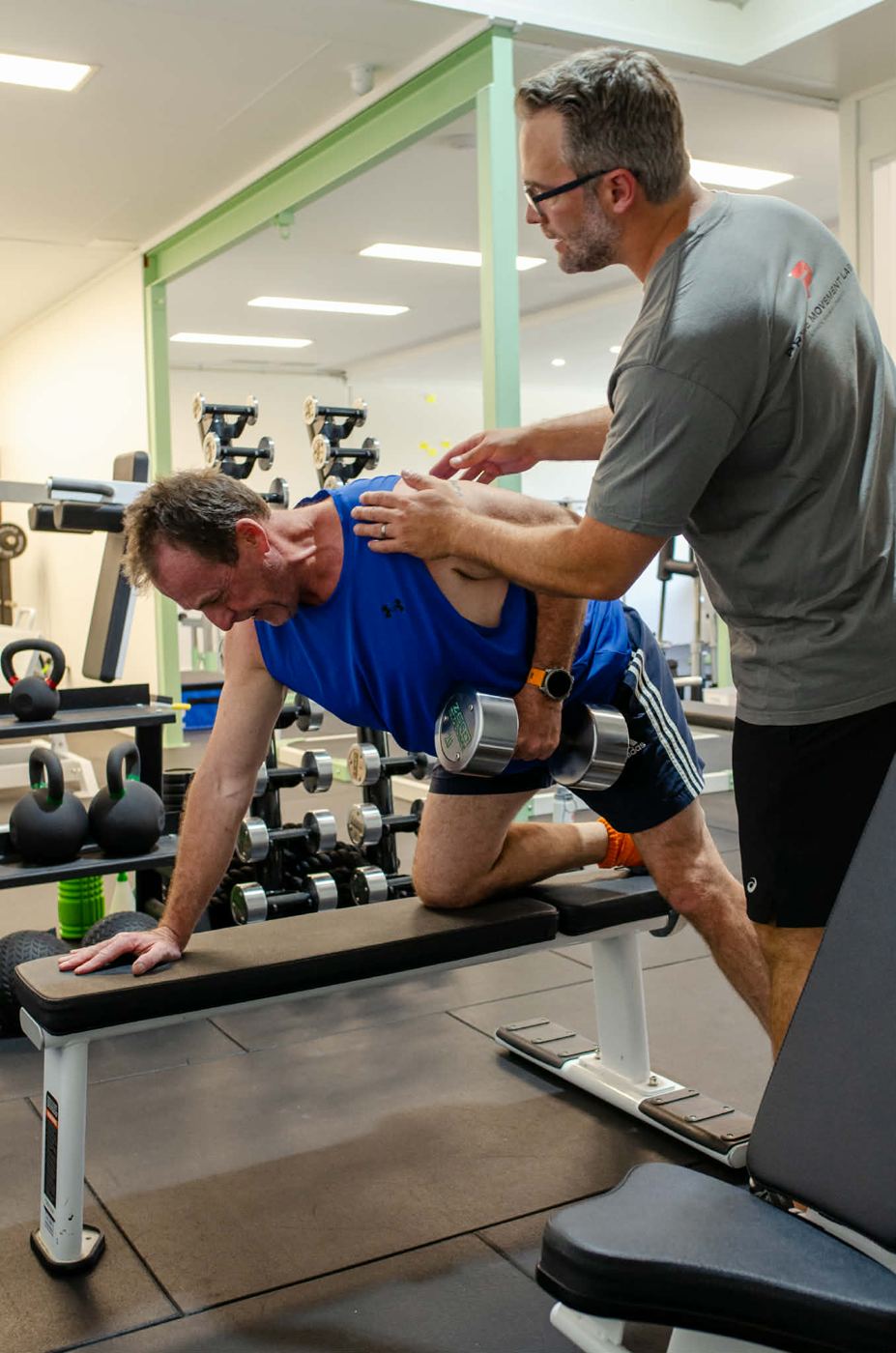 Mathew guiding a client's shoulder blade during a single-arm dumbbell row