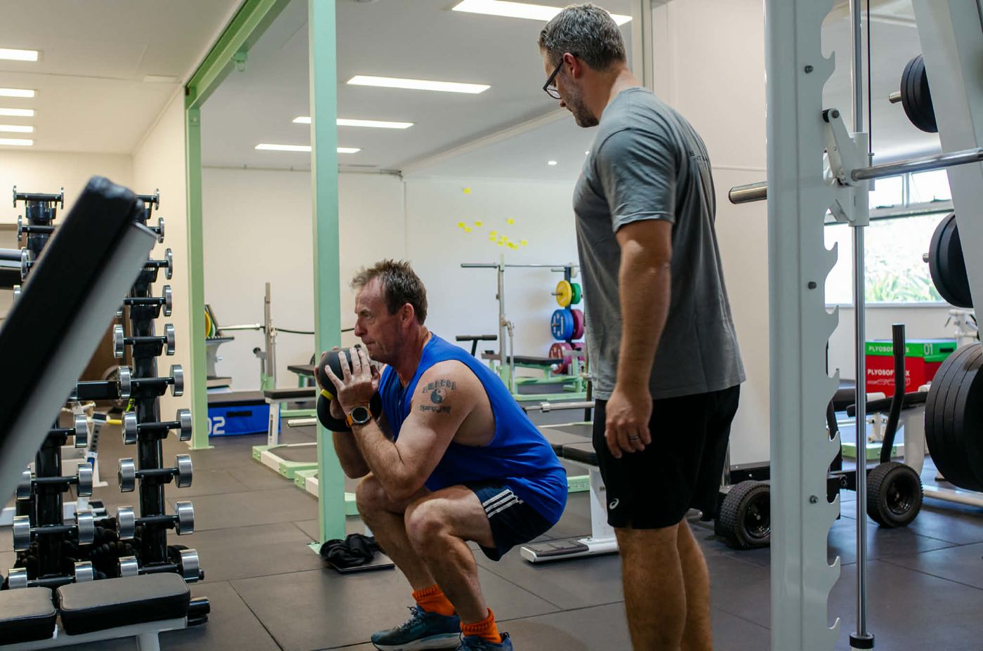 Client performing a goblet squat while Mathew watches his position