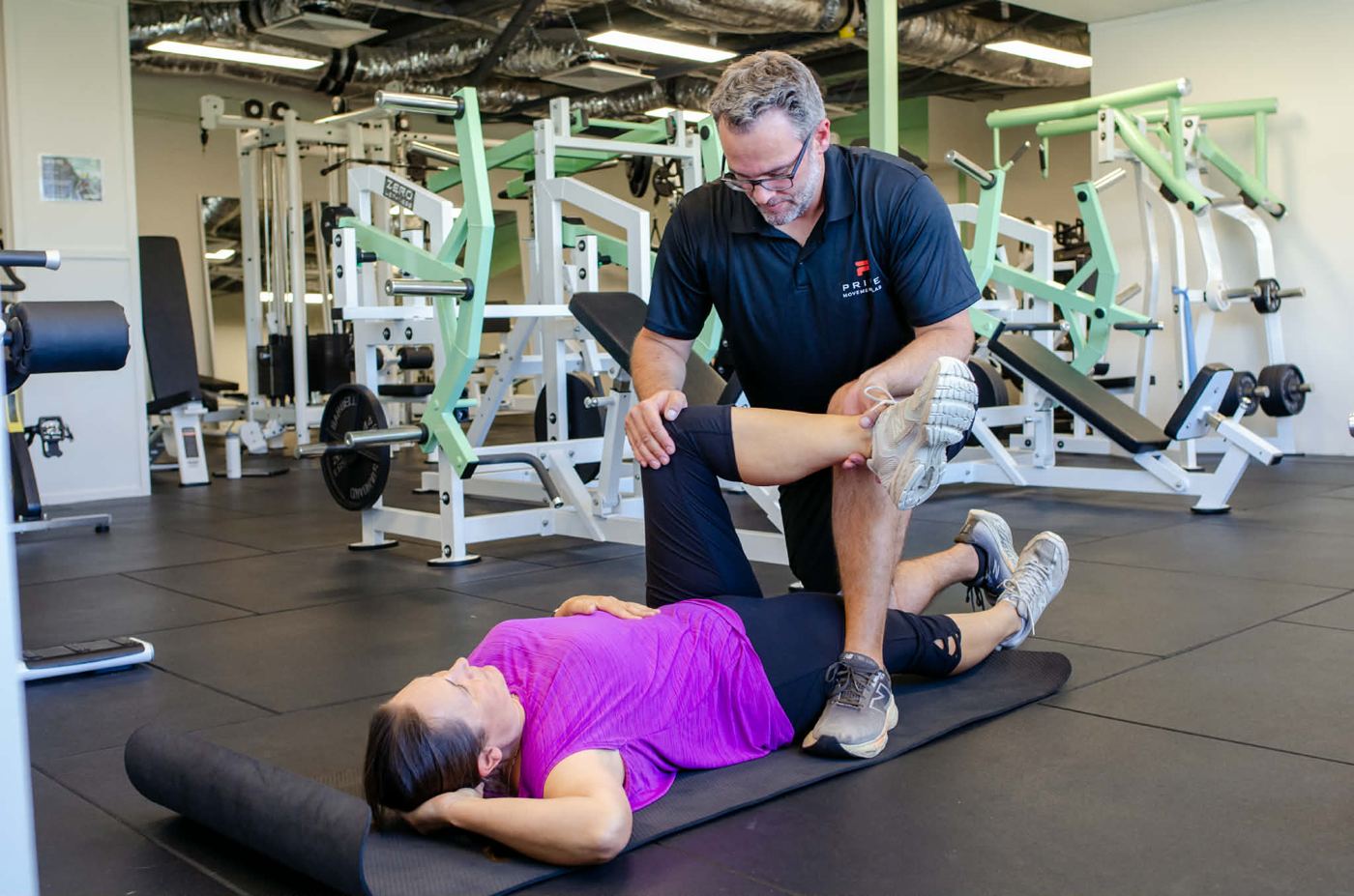 Mathew assessing a client's hip mobility on the gym floor
