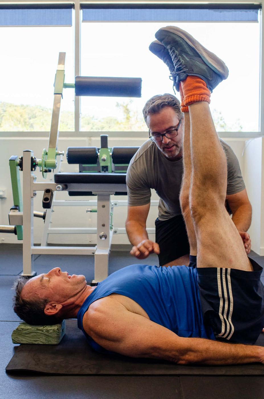 Mathew coaching a client through a controlled leg raise on the floor